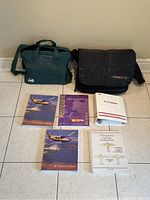 Photo showing the full set of five pilot training books and two carry bags arranged neatly on floor tiles.