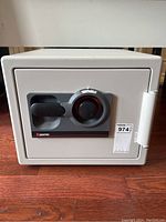 Front view of closed light gray safe on wood floor