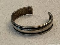 Front angle view showing hammered textured center band with smooth edges of the handmade silver cuff bracelet.