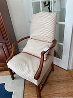 Side angle showing wooden arms and floral upholstery on arm chair with decorative cushion.