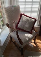 Overall front view of the arm chair showing upholstery, wood frame and one pillow on the seat