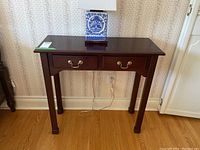 Front view of the wood console table with two small drawers and brass handles, showing the overall design and finish.