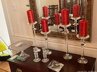 Four crystal candle holders with red candles, glass cake stand, smaller candle holders, ashtray.