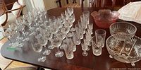 Wide view of the collection on a wooden table showing multiple crystal stemware and bowls with pinwheel patterns and clear glass colors.