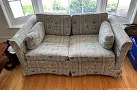 Front view of Ethan Allen Traditional Classics loveseat showing floral motif fabric upholstery and bolster pillows.