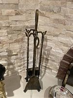 Front view of the fireplace tool set on its stand showing all tools grouped together in a triangular arrangement.