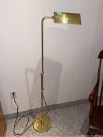 Full view of the metal floor lamp showing tall adjustable pole, rectangular lamp shade, round base, and power cord.