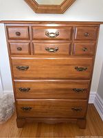 Front view of the dresser showing all four drawers with brass handles and round knobs, in good condition showing wood grain and finish.