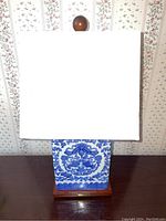 Full view of the Ralph Lauren ceramic table lamp with white lampshade and wooden finial on top.