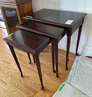 View of three Gibbard solid mahogany nesting tables stacked together, showing contoured tops and legs with dark polished finish.