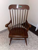 Front view of wooden spindle back vintage rocking chair showing seat, armrests, and rocker base