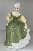 Front view of Royal Doulton Fair Maiden figurine showing detailed face, green dress with yellow sleeves, and white ruffles.