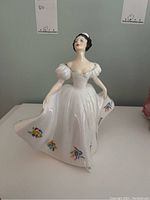 Front view of Royal Doulton Kate figurine in white dress with floral accents, showing front details.