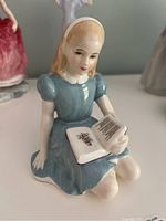 Front view of Royal Doulton Alice HN 2158 figurine showing the girl in blue dress reading a book