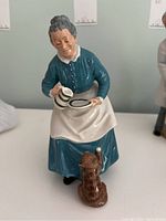 Front view of the Royal Doulton porcelain figurine depicting an elderly woman with a cat, holding a tray with a jug and cup.