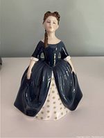 Front view of Royal Doulton Debbie HN 2385 figurine in dark blue dress with white and gold star patterned underskirt.
