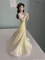 Front angle of the Royal Doulton Chelsea Kathryn figurine showing the face, hair, and full yellow dress with white off-shoulder detail.