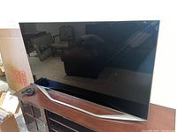 Front view of the Samsung TV on its stand with HDMI cable coiled beside it