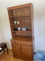 Front view of Kroehler Cape Cod wooden hutch showing three open upper shelves, dovetailed drawer with four knobs, and two-door lower cabinet with wood slat design.