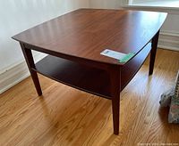 View of the side table corner showing the wood grain and lower shelf.