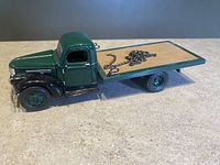 Side view of the detailed 1941 Chevy flatbed toy truck showing green cab, wooden flatbed and metal chain on bed.