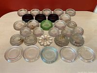 Top view showing all glass pieces laid out on a surface, including clear, green, and dark brown circular coasters/sliders and decorative jar lids