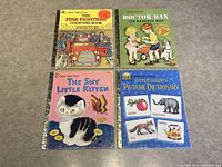 Four Little Golden Books laid out on carpet: The Shy Little Kitten, The Firefighters Counting Book, Doctor Dan: The Bandage Man, and Little Golden Picture Dictionary.