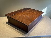 Closed wooden storage case showing top and side with rustic finish and patina.