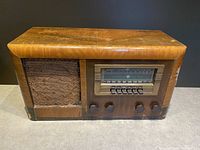 Front view of vintage General Electric H-61 short wave broadcast radio with wooden case, showing speaker on left and tuning dial with control knobs on right.