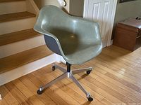 Full front-angle view showing shell seat, integrated arms and aluminum star base with casters