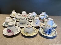 Photo showing all 14 teacups upside down on their matching saucers, highlighting the base patterns and the saucer designs.