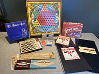 Vintage games lot with Chinese Checkers board, Yahtzee game box, Monopoly booklet, Knights Tour box, checkers board, cribbage game boxed set, and multiple decks of cards.