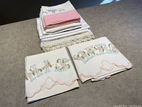 Pile of folded embroidered pillow cases featuring text 'His' and 'Hers' and floral embroidery