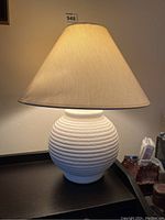 Full front view of desk lamp lit to show overall design and shape.