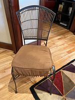 Front view of metal frame chair showing curved backrest and removable cushioned seat pad in brown fabric.