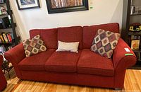 Front view of red fabric sofa with three cushions
