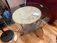 Top down view of side table showing clear glass top and stone-colored ceramic center base with metal legs.