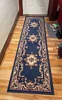 Full length view of blue runner rug with floral medallion pattern on wooden floor