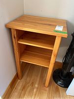 Front view of wood side table showing two shelves and enclosed sides, natural wood grain finish.