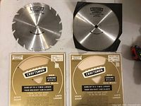 Two 10-inch Craftsman saw blades displayed on surface with original packaging beneath them.