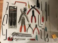Full overview of assorted hand tools on a white background including pliers, hex keys, hole punch, pipe cutter, and more.