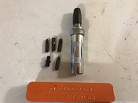Full view of impact driver, five bits, and orange metal case