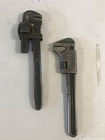 Two vintage British pipe wrenches laid side by side on a white surface.