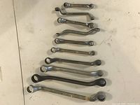 Overview of 11 vintage British spanner wrenches arranged in descending size order on a white surface, showing varying lengths and some curved shapes.