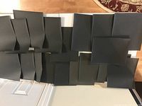 Top-down view of approximately 18 large sheets of black waterproof sandpaper laid out on a flat surface, showing size and quantity