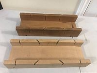 Top down view of two wooden mitre boxes showing angled slots for guiding saw cuts