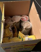 Opened box showing multiple yellow packs of Lysol Disinfecting Wipes and several containers with red and blue labels of Bar Keepers Friend Cleanser wrapped in plastic bags.