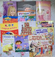 Photo of 13 children's books showing various storybook and activity titles including Hannah Montana, Phonics, All Delicious, and others.