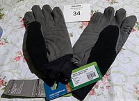 Pair of grey and black Glide XC gloves lying flat showing palm and tops, with tags attached indicating new condition and cross-country skiing use.
