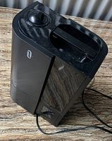 Top and angled view of black ultrasonic humidifier showing control knob, water tank, and power cord on a wooden surface.